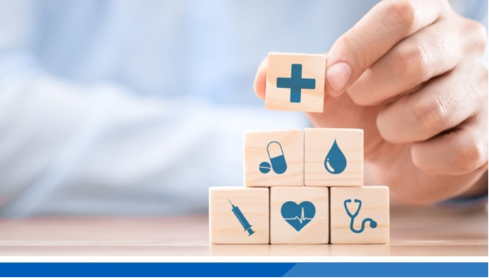 A hand stacking building blocks with health symbols on