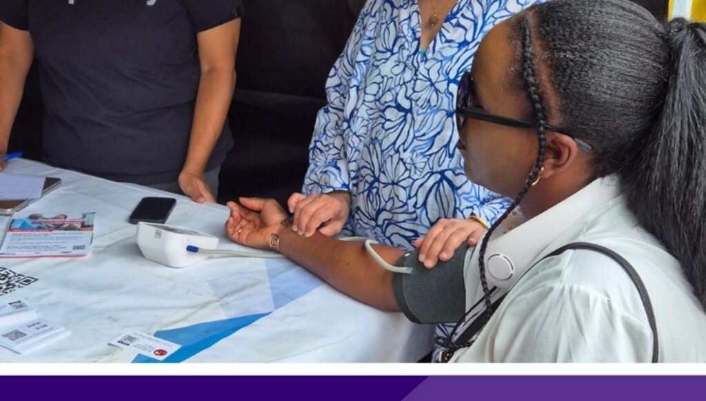 A person sitting at a table having their blood pressure taken