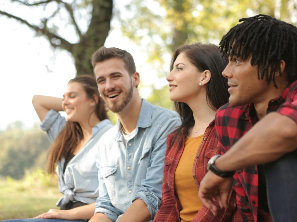 A group of four young adults laughing in the park