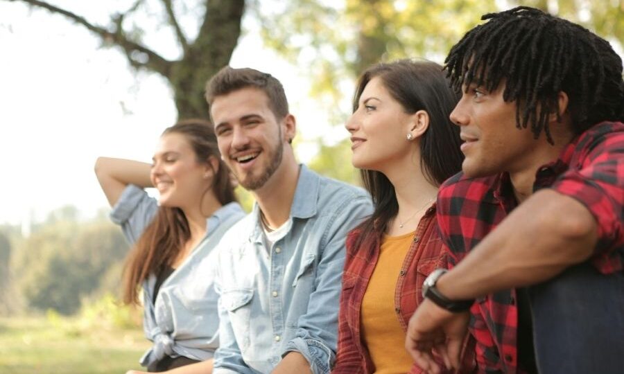 A group of four young adults laughing in the park