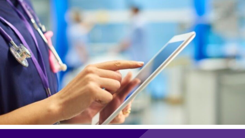 Close up of a clinician on a hospital ward using a tablet.
