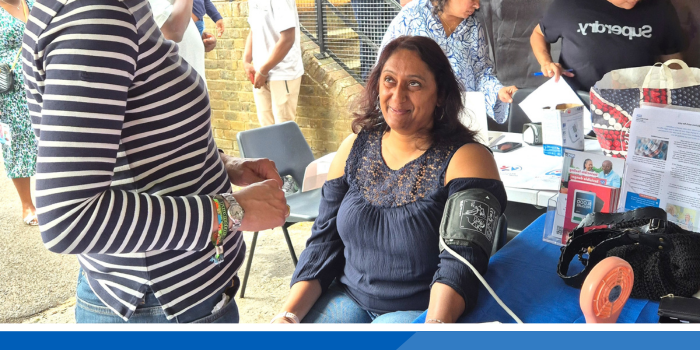 Lady smiling whilst having her blood pressure taken at a community event
