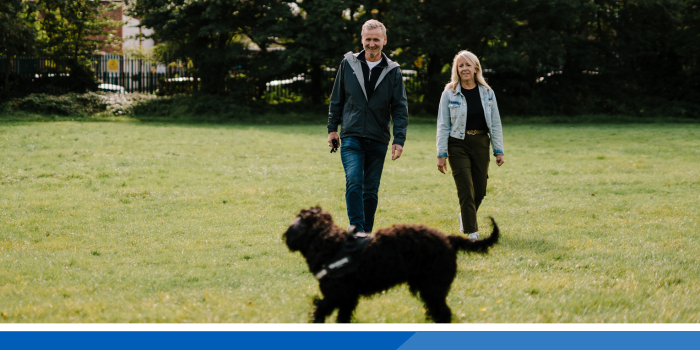 Man and lady walking their dog in a field