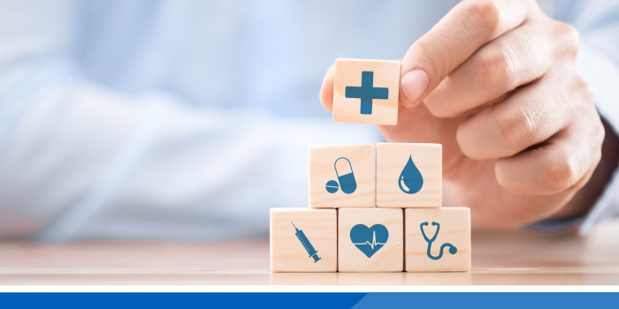 Hand stacking building blocks which have health related icon images on them.