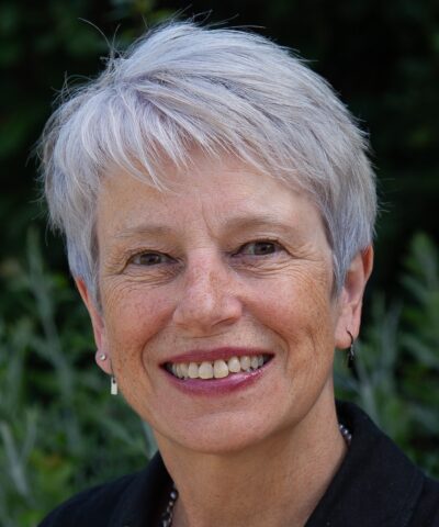Head shot of a white middle-aged woman, smiling, with short, grey hair.
