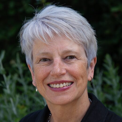 Head shot of a white middle-aged woman, smiling, with short, grey hair.