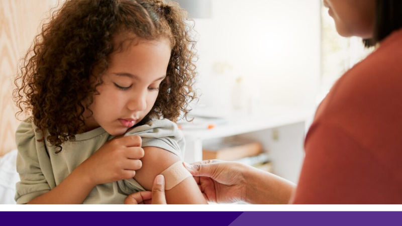 Young child having plaster put on arm following a vaccination.