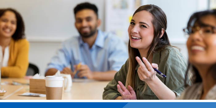 4 people sat around a table smiling in a meeting