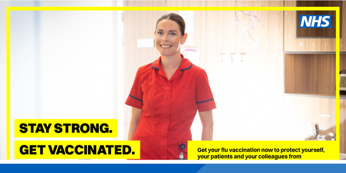 A nurse smiling at the camera dressed in a red uniform. The wording says "Stay strong, get vaccinated"