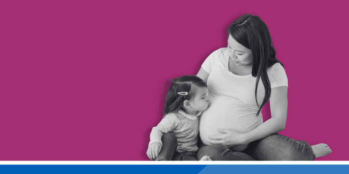 Pregnant woman with a toddler kissing her stomach