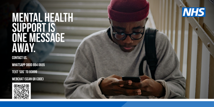 Photo of a young man in a red beanie, glasses and a grey sweatshirt sitting on outdoor stone steps, looking down at his phone. White headline text at top left reads "Mental health support is one message away." Contact details on the graphic: WhatsApp 0800 884 0655; text 'SOS' to 80899; webchat via a QR code. Small print: NXG Thrive provides a free 24/7 confidential mental health crisis text service. You don't have to do this alone. The NHS logo is at top right and the NXG Thrive logo at bottom right.